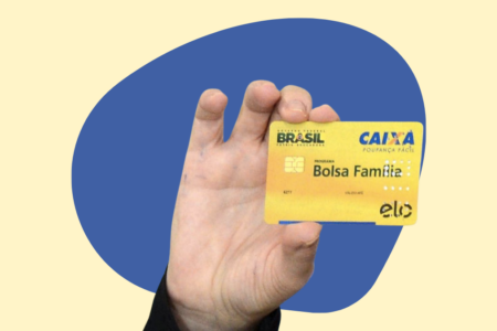 Uma mão segurando o cartão do Bolsa Família
